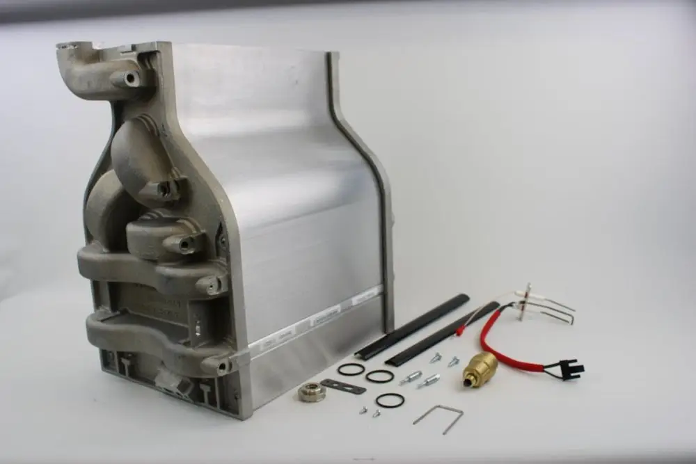 BOSCH Wärmetauscher aus Aluminium, mit Anschlusskomponenten und Dichtungen, in einer Anordnung auf hellem Hintergrund.
